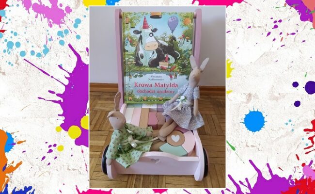 Krowa Matylda obchodzi urodziny zdjęcie główne książka ustawiona na wózku z klockami i dwoma ręcznie robionymi królikami szmaciankami